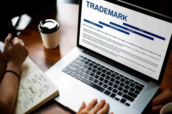 Person reading trade mark information on a laptop while taking notes