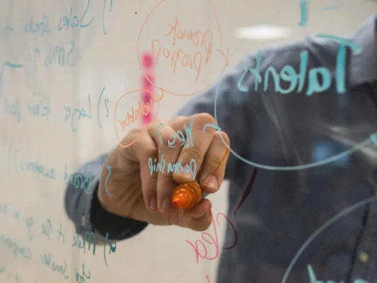 Person writing notes on a glass board, representing a response to an adverse report